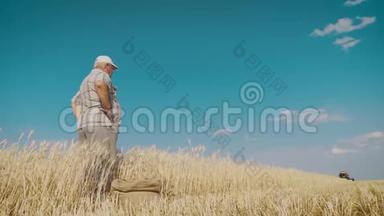 成熟的农民在联合收割机收割时站在麦田里，他控制着收割过程，一个袋子