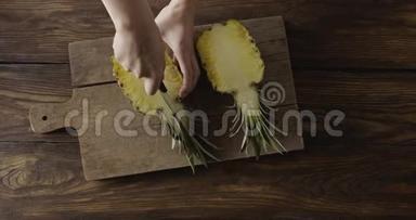 女`的手在木切割板上的一个打着打着打着打着打着打着打着打着的小口的小口，把新鲜多汁的黄色天然奇葩菠萝的一半切开.. 顶级