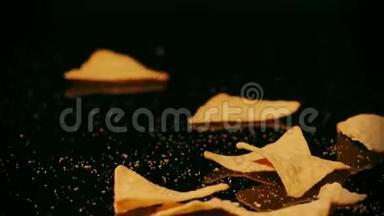 破碎的玉米饼碎片落在黑色背景下，慢镜头