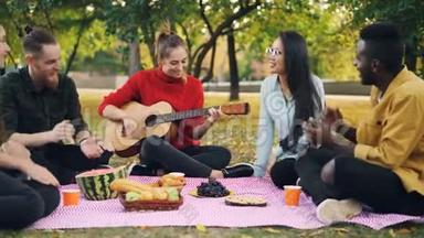 许多朋友在公园里唱歌，拍手，美丽的女孩在野餐时弹吉他