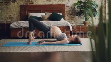 漂亮的<strong>孕妇</strong>穿着舒适的<strong>孕妇</strong>装在卧室的瑜伽垫上做运动。 健康