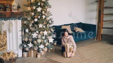 年轻女子正把礼物盒带到圣诞树下，放在圣诞树下，然后看礼物和礼物