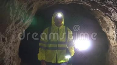 画像男志愿者救援者手里拿着手电筒正在洞穴里寻找一个人，慢一点