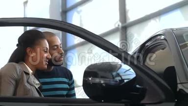 一对新婚夫妇在检查一辆新车时竖起大拇指