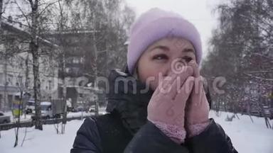 街上一位年轻女子的肖像，她在冬天的公园里散步时，双臂呼吸以保暖。 慢慢