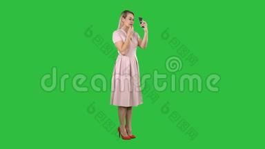 涂<strong>口红的</strong>女人在绿色屏幕上看着她<strong>的</strong>手机，Chroma键。