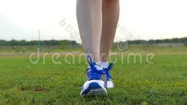 穿<strong>运动鞋</strong>的女孩在镜头方向的绿草上。 运动和<strong>户外</strong>娱乐活动..