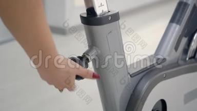 女人在她的旋转自行车上调整座位。