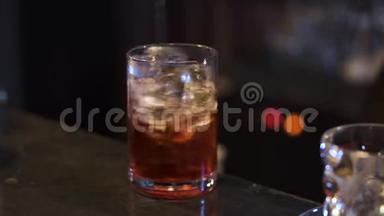 酒保在酒吧里做鸡尾酒。 酒精手把酒精和冰块混合在玻璃里。 夜生活