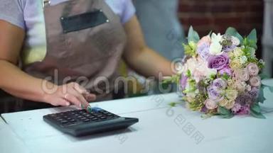 在一家花店的特写中，女花店用计算器计算花束的成本