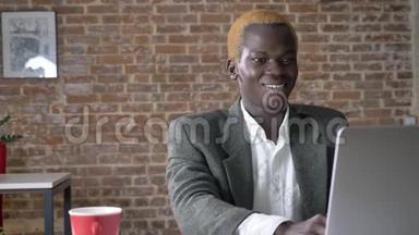 年轻成功的非洲商人在笔记本电脑上打字，在现代办公室里<strong>欢呼</strong>，快乐的<strong>胜利</strong>者微笑
