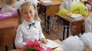 小女孩坐在学校的班级里学习。 可爱的女孩在上课时看相机的肖像。