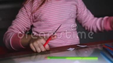 可爱的小女孩的特写镜头`她的手穿着粉<strong>红色</strong>的毛衣，用剪刀<strong>剪纸</strong>，用铅笔画画。