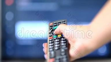 慢动作的女人看电视，按下遥控器上的按钮。 手拿着电视遥控器关掉