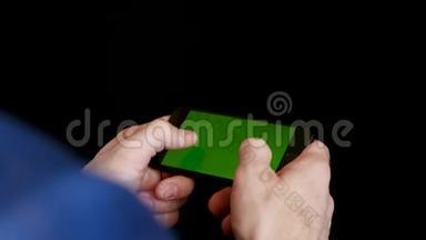 一个工作场所的男人用智能手机用绿色屏幕，检查财务报告，点击屏幕，打字