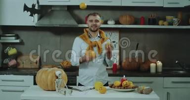 万圣节的心情在厨房里，一个男人在镜头前摆弄着迷你橙色，时尚的男人，好心情。