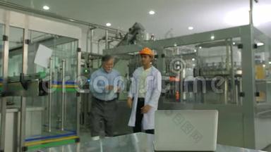 高级经理与机械工人检查生产计划与瓶子生产线在后台。