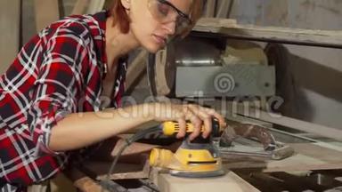 勤奋的女木匠在车间打磨木材