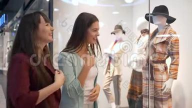 购物者的生活方式，快乐的女朋友在商店橱窗里讨论时尚的人体模特新系列服装