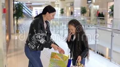 时尚的年轻女孩和妹妹在购物中心散步和购物。
