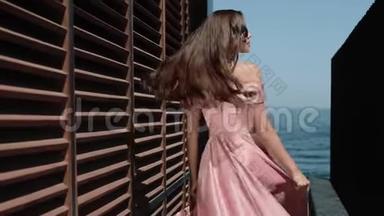 在欢乐的夏日里，优雅的女孩穿着华丽的服装在海滨酒店大楼附近。