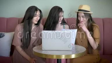 三个活跃的女朋友在网上商店里看<strong>宣传海报</strong>，选择新衣服，笑着在网上玩