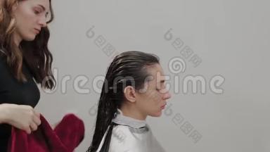 美容<strong>美发</strong>沙龙。 一个理发师正在用毛巾把客户的头发洗了之后，在水槽里擦拭。