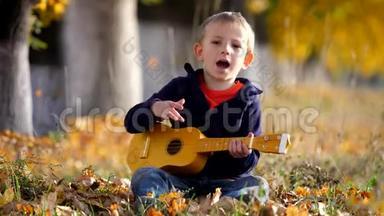 有趣的孩子在吉他边唱歌的肖像，快乐的孩子在公园里拍手