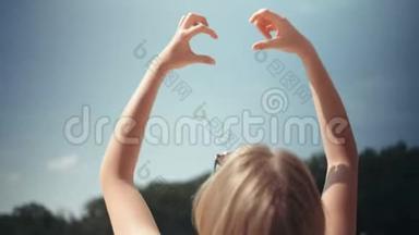 年轻女子举起双手向天空举起心形。