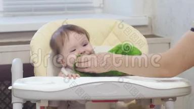妈妈擦着婴儿的脸。 宝宝学会用勺子吃粥。 婴儿是反复无常的，坐在高椅上哭泣