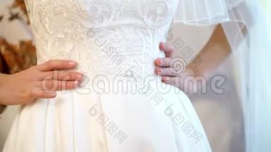 新娘费。新娘为婚礼穿好衣服。新娘手的特写，用一个温和的美甲，对着