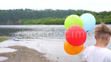 一个青少年拿着气球。 在湖边的大自然中度过暑假。 庆祝和乐趣。 孩子`生日