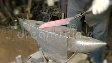在锻造厂用金属制造刀。 紧紧抓住铁匠`双手在铁锤上敲打铁水