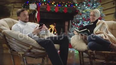 男人和女人在圣诞夜边看书边用智能手机聊天
