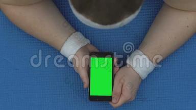 运动员观看在线<strong>健身视频</strong>，躺在垫子上的智能手机，锻炼休息