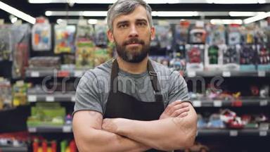 有<strong>经验</strong>的穿着围裙的英俊大胡子推销员站在超市<strong>经验</strong>的推销员站在超市的玩具部，看着