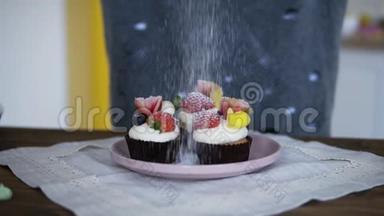 面包师装饰美味，花哨装饰的纸杯蛋糕。 糖在蛋糕上撒上新鲜的草莓和奶油
