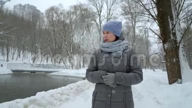 雪天独自在冬季公园散步的成年妇女