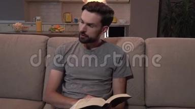 大胡子坐在沙发上看厚厚的书。 他<strong>翻开</strong>书页。 然后，人类向左看，继续<strong>阅读</strong>。