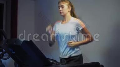 年轻漂亮的女孩在健身中心跑步机上跑步。