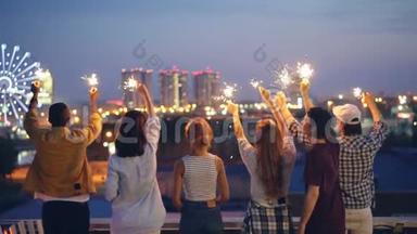 快乐的青年朋友们慢悠悠地举着星星之火，举起双手站在屋顶上欣赏美景