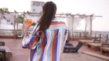 一位奢华时尚的女士，端着一杯鸡尾酒走着，穿着木制的彩色丝绸礼服
