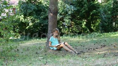 夏天在树下看书。 一个十几岁的女孩在户外看书