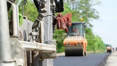 修公路，道路建设工程.. 在前景中，在铺设沥青的机器上，工人留下了特殊的橙色