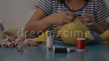 女人在家里的桌子上缝制和固定泰迪熊娃娃。