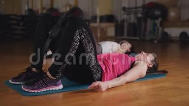 普拉提在健身房上课。两个女人在健身房用健身环做普拉提练习。