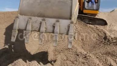 挖掘机正在准备一堆沙子，以便在建筑工地的卡车上装载