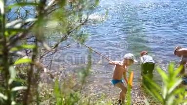 三个孩子站在一条山河的岸边.. 他们向河里扔石头。 兄弟俩过暑假