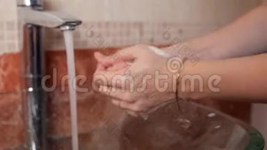 一个<strong>年</strong>轻的女孩站在浴室里，用透明的水盆洗手