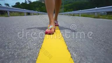 一个女孩的腿沿着一条黄色的分割条沿着马路走。